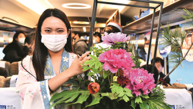 2021年12月26日，在菏泽东至北京南的列车上，一位工作人员在展示牡丹插花作品。（xinhua）_副本.jpg