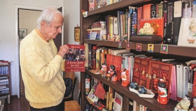 2016年11月8日，在秘鲁首都利马的家中，汉学家吉叶墨从书架上取出自传图集《现在我是谁？》，图集中收录了他参与拍摄的25部中国电影的剧照。（XINHUA）.jpg